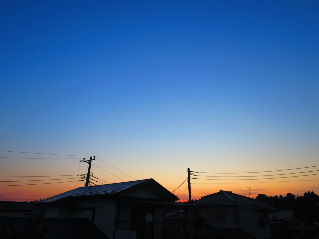 SILHOUETTE HOUSES AGAINST CLEAR BLUE SKY AT SUNSET