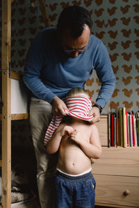 Father dressing daughter at home