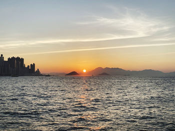 Scenic view of sea and buildings against sky during sunset