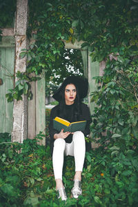 Portrait of young woman sitting on book