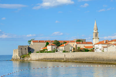 Buildings by river against sky