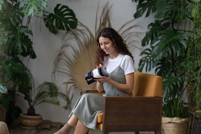 Interested young woman hold glasses for virtual reality simulation sitting in home garden space