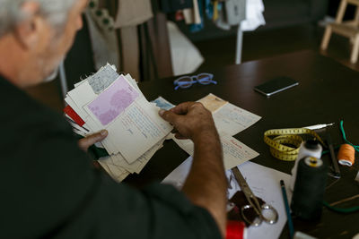Mature male tailor looking at fabric swatch in work studio