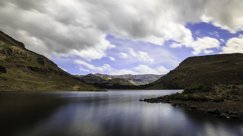 Scenic view of river by mountains against sky