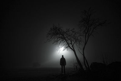 Rear view of silhouette man standing on field at night