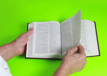 Close-up of hand holding book against gray background