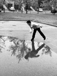 Playful boy standing by puddle on footpath