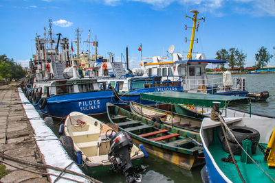 Boats moored at harbor against sky