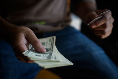 Midsection of man holding paper currency and credit card