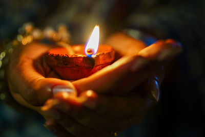 Close-up of hand holding lit candles