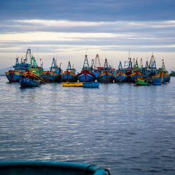 Boats moored at harbor against sky