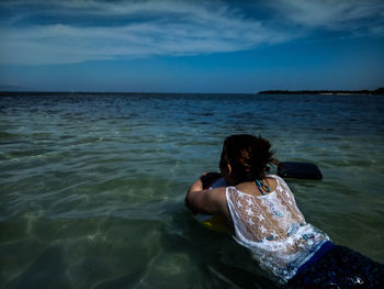 Rear view of woman in sea against sky