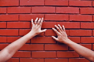 Cropped image of women touching brick wall