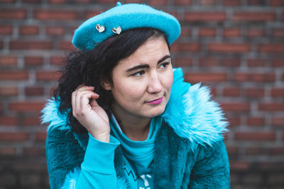 Close-up of young woman looking away against brick wall