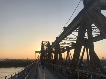 Bridge over river against clear sky during sunset