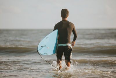 Rear view of shirtless man playing on beach