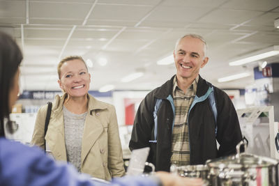 Smiling mature customers looking at young owner in store