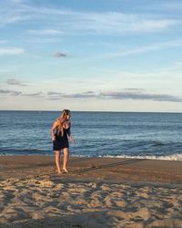 Woman walking on shore at beach against sky