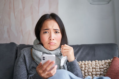 Portrait of young woman sitting on sofa at home