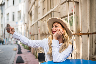 Portrait of young woman using mobile phone in city