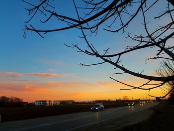 Cars on road against sky during sunset