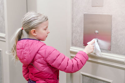 Girl cleaning metal on wall