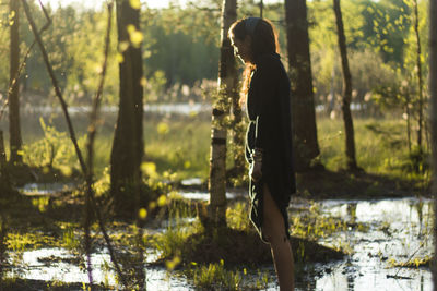 Side view of woman standing in lake at forest