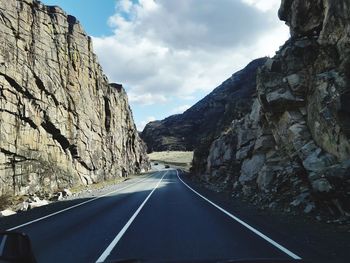 Empty road along rocky mountains