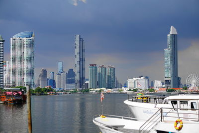 Sea by modern buildings against sky in city