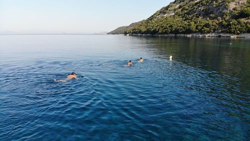 People swimming in sea against sky