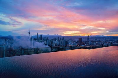 View of cityscape against cloudy sky during sunset