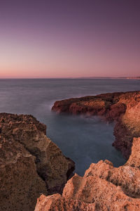 Rocks on beach against sky during sunset