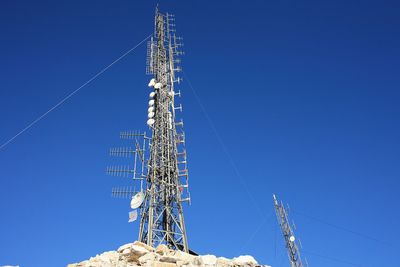 Low angle view of communications tower against blue sky