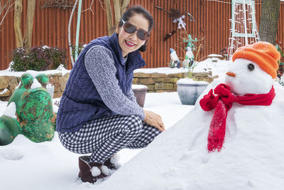 Smiling young woman with ice cream in snow