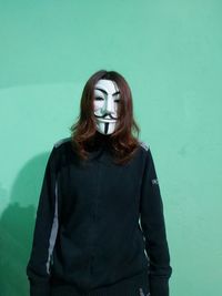 Portrait of young woman standing against wall