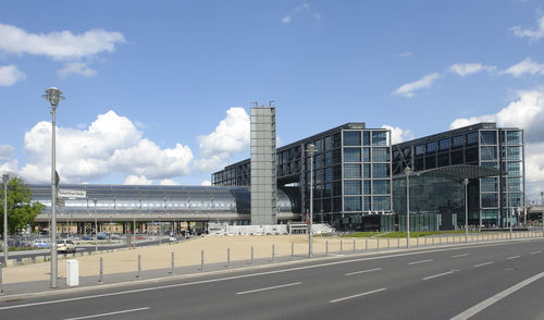 City street by modern buildings against sky