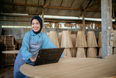 Portrait of young woman using digital tablet while sitting on table