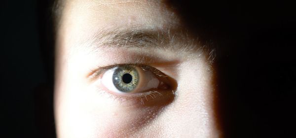 Close-up portrait of human eye on black background