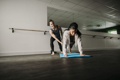 Female personal trainers helps her female client do a plank