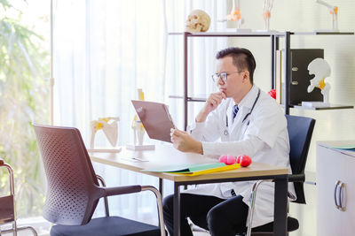 Midsection of woman using mobile phone while sitting on table