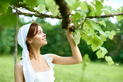 Portrait of young woman standing against plants