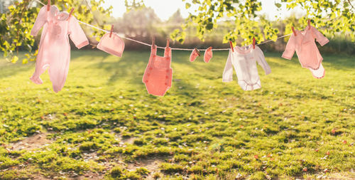 Pink newborn baby girl clothes hanging outdoors at sunset. focus on clothes