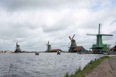 Traditional windmill by river against sky