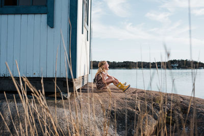 Young woman sitting on boat in lake against sky