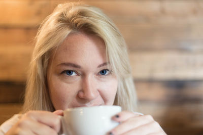 Portrait of young woman with blond hair drinking coffee 