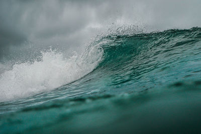 Close-up of wave splashing on sea against sky