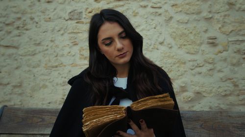 Portrait of young woman standing against wall