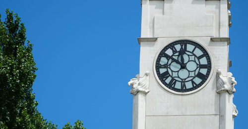 Low angle view of clock tower against blue sky