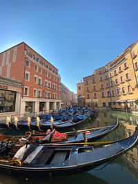 Canal amidst buildings against clear blue sky