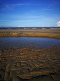 Scenic view of beach against blue sky